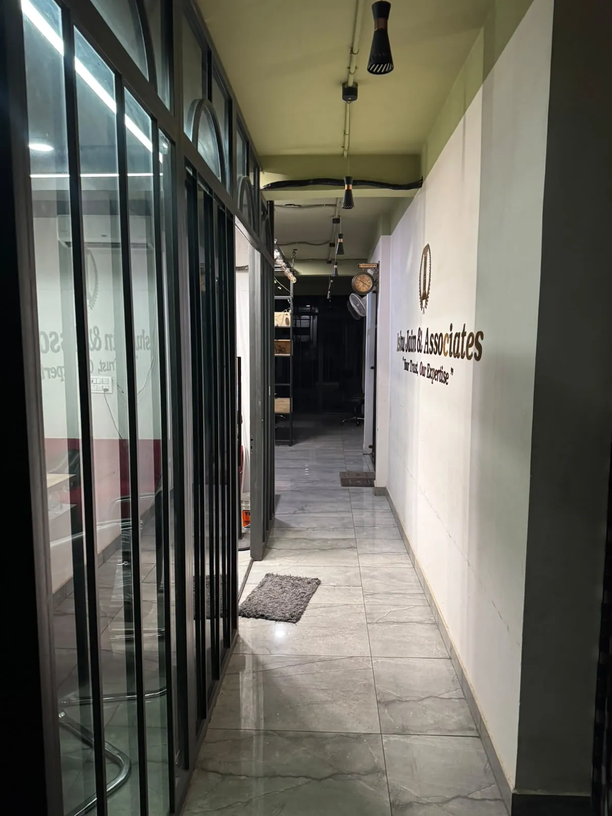 The office corridor, with glass-fronted cabins on one side and the firm's name on the wall