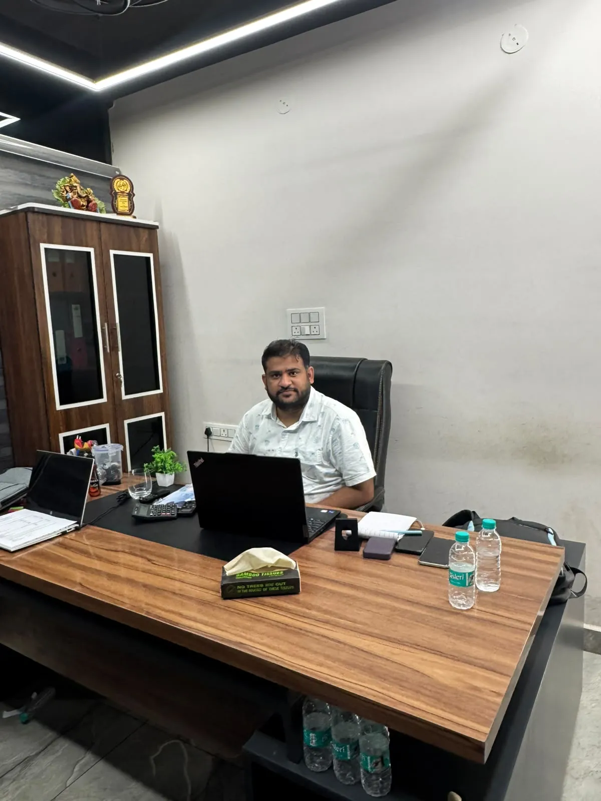 A cabin with a wooden desk, laptops and a file cabinet, with a team member at work