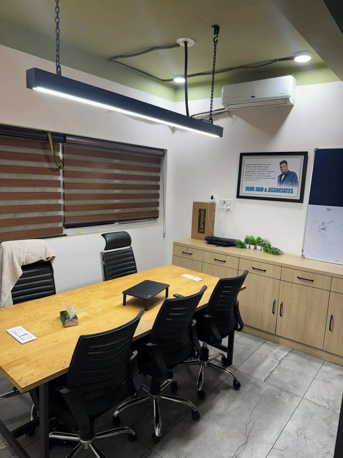 The meeting room, with a wooden table, black chairs, storage units and a whiteboard